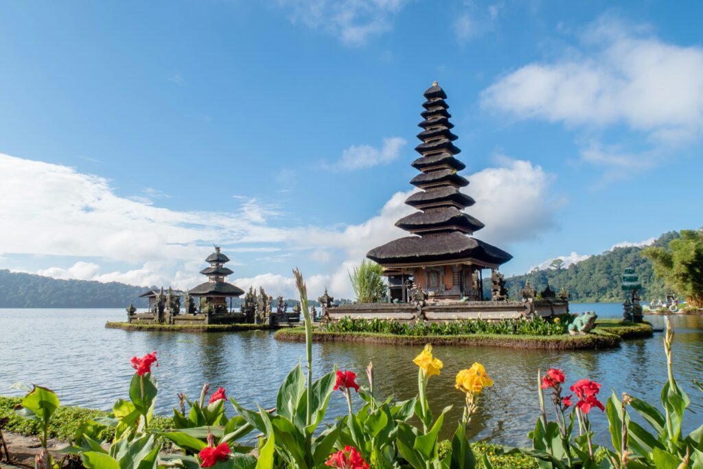 Ulun Danu Beratan Temple on a lake in Bali with flowers in the foreground and mountains in the background-Destination wedding site