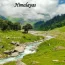 A pristine glacial river flowing through a vibrant green Himalayan valley with camping tents, a paradise for Indian travel.