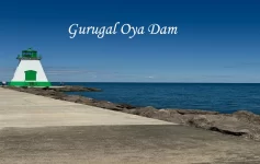 A white and green lighthouse on a stone pier next to the deep blue sea, on the scenic route toward Sri Lanka's hill stations.
