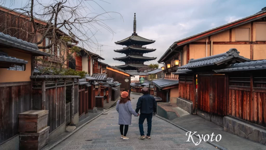 A couple holding hands and walking down a historic cobblestone street toward the Yasaka Pagoda in the Higashiyama district of Kyoto during a 7 days tour in Japan.