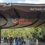 Visitors gathering at the main entrance of Bird Paradise Singapore under a large modern canopy with the colorful park logo