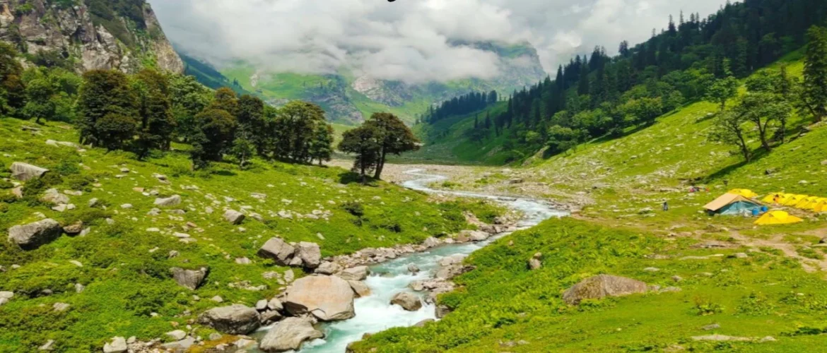 Indian Travel destination featuring the lush Himalayan valley with a flowing river, green meadows, pine forests, mountain peaks, and camping tents.