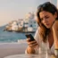 Woman sitting at a seaside café in Greece looking concerned at her phone while checking her mobile data connection