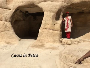 Woman standing inside one of the ancient rock-cut sandstone caves in Petra, Jordan.