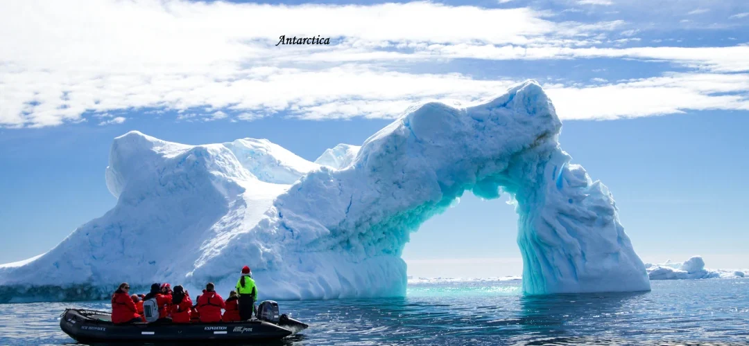 Antarctica tourism 2026 Antarctica glacier arch with tourists exploring by boat