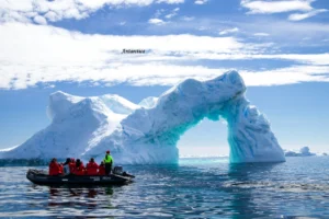 Antarctica tourism 2026 Antarctica glacier arch with tourists exploring by boat