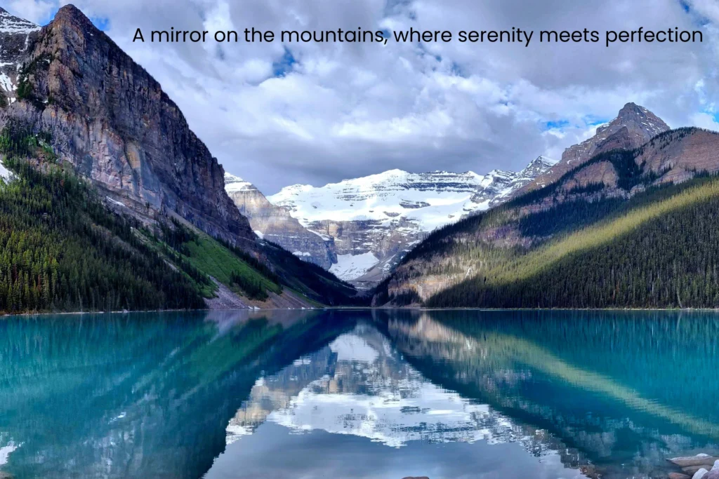 Still waters of Lake Louise perfectly reflecting snow-capped mountains and glacier under a cloudy sky
